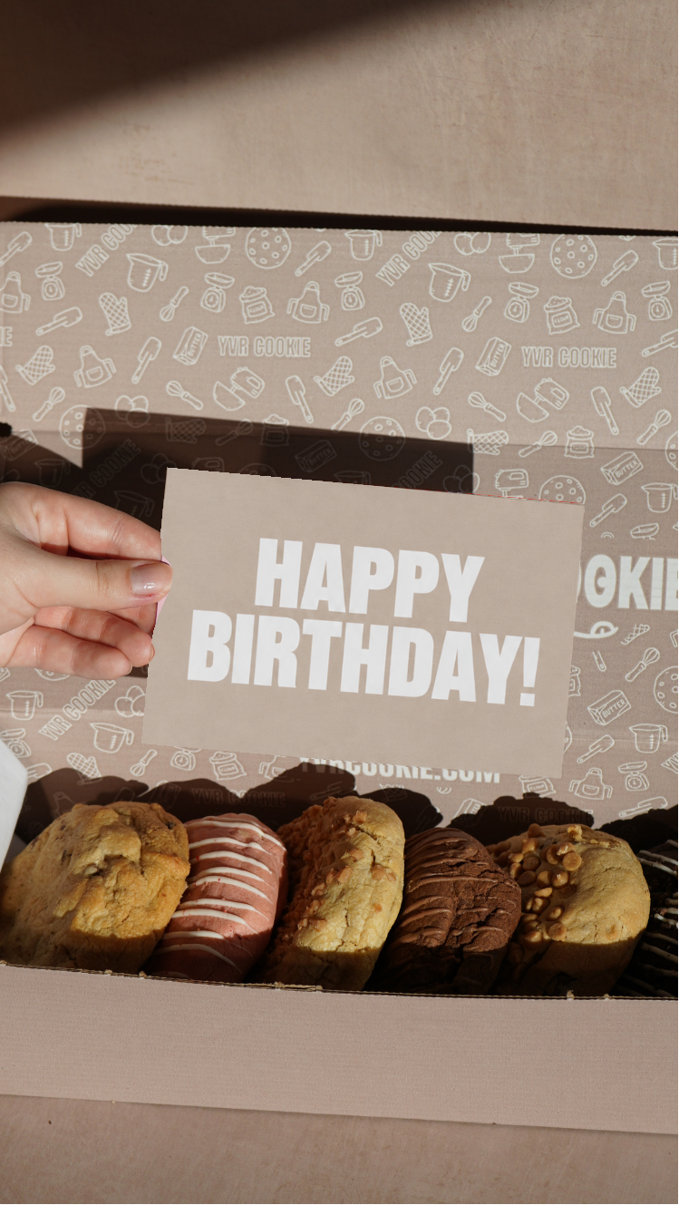 Happy Birthday occasion card held above a box of jumbo YVR Cookies